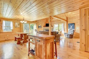Ein Interieur einer Holzhütte mit Essbereich, Sitzgelegenheiten und Kamin.