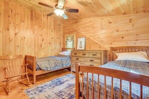 Eine Hütte mit zwei Holzbetten, einem Schaukelstuhl, einem Schminktisch und einem Deckenventilator.
