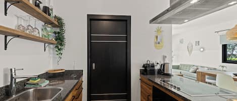 A modern kitchen with a black door, stainless steel appliances, and a dining area with a sofa and table.