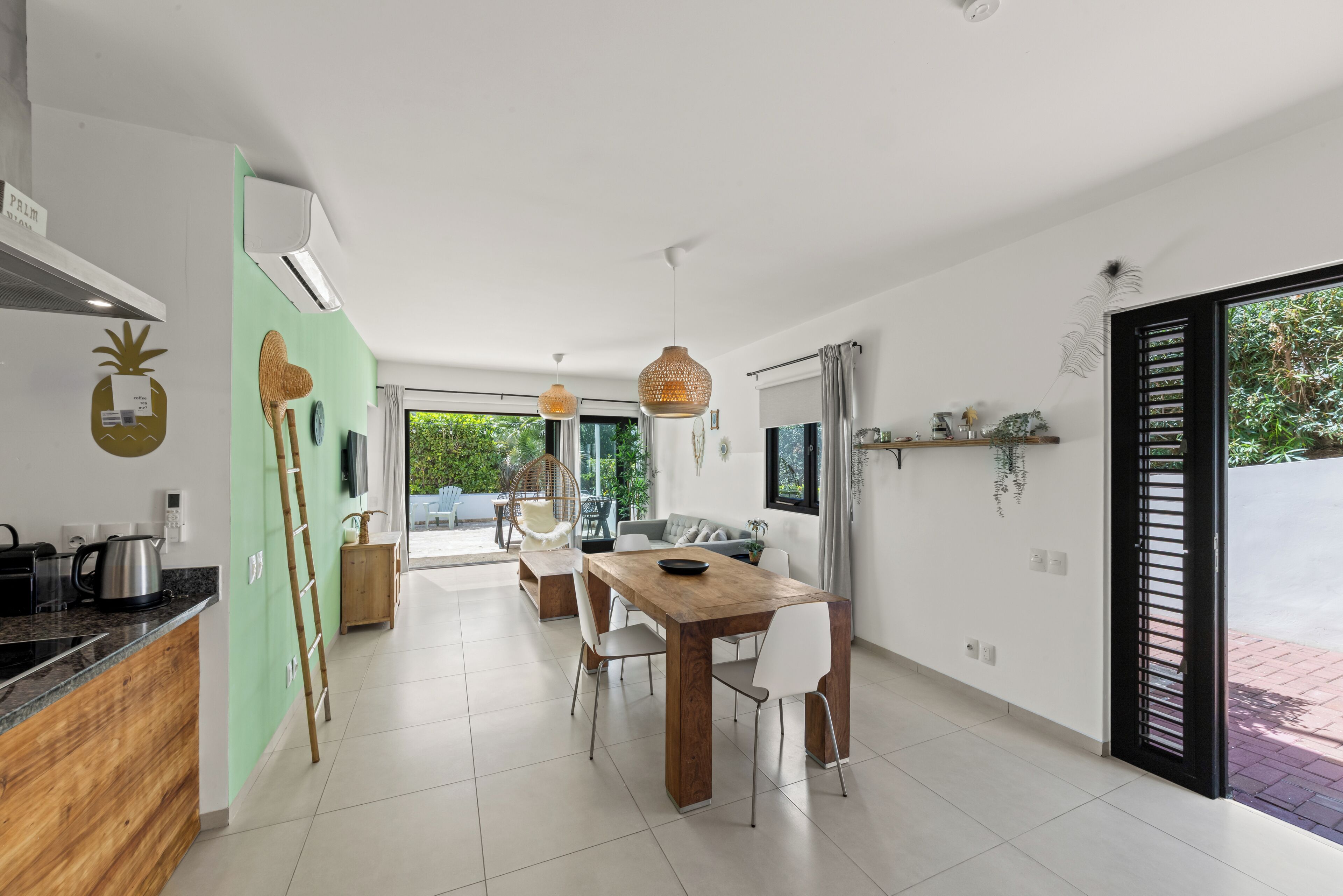 A modern kitchen with a dining area, featuring a wooden table, chairs, and a coffee machine.