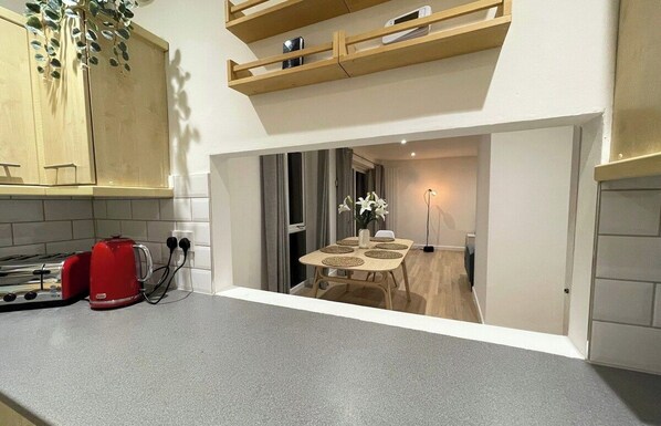 Una cocina moderna con un tostador integrado, un armario de madera y un comedor con una mesa y sillas.