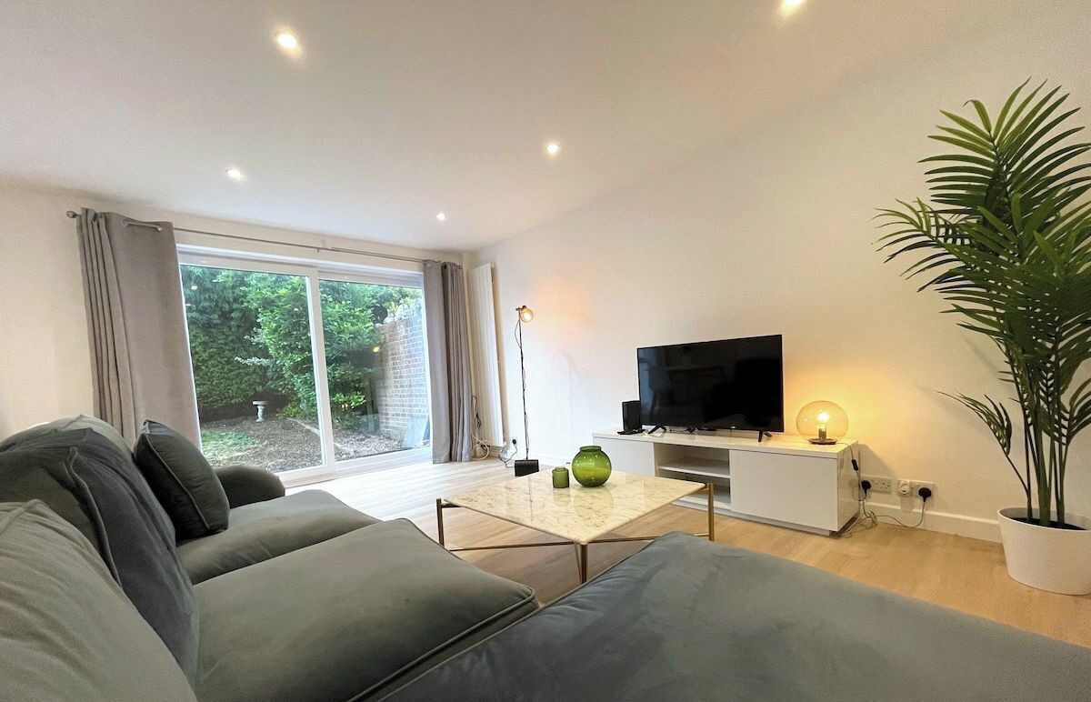 Un salon moderne avec un canapé, un téléviseur, une table basse et une plante en pot.