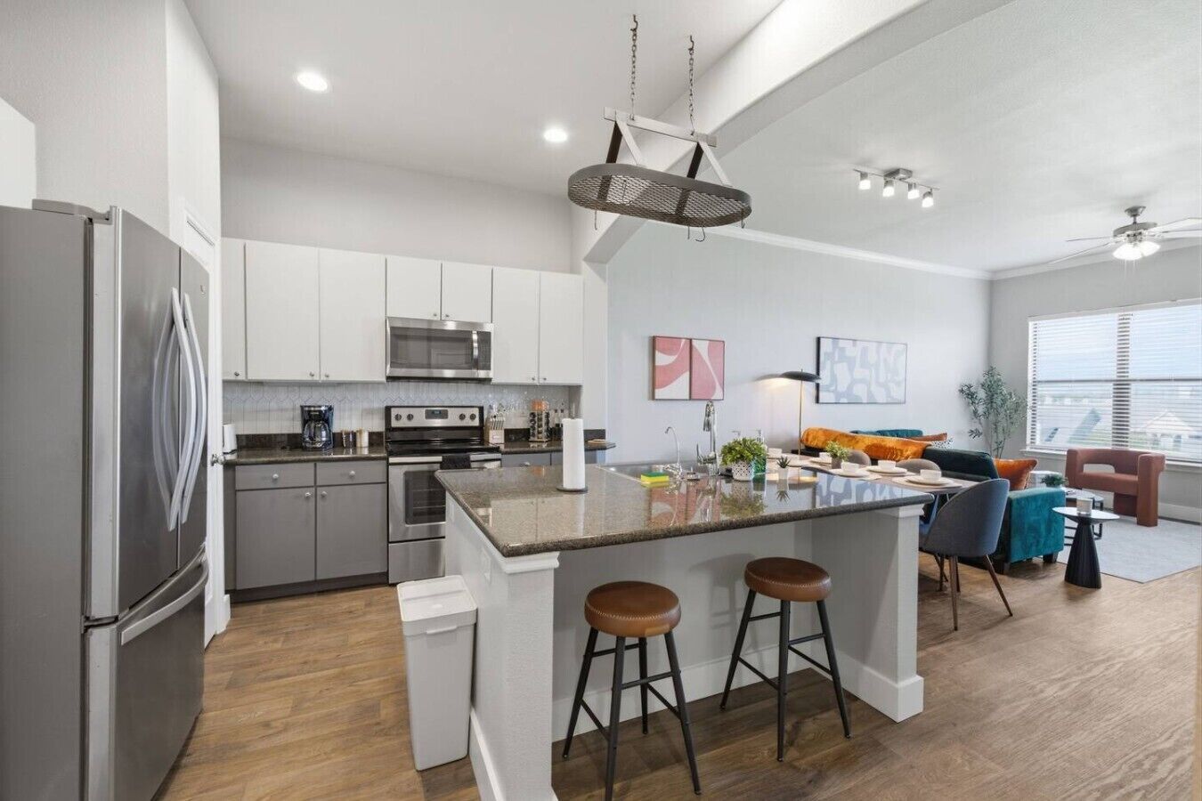 Een moderne keuken met roestvrijstalen apparatuur, een centraal kookeiland met krukken, en een eethoek met een bank en stoelen.