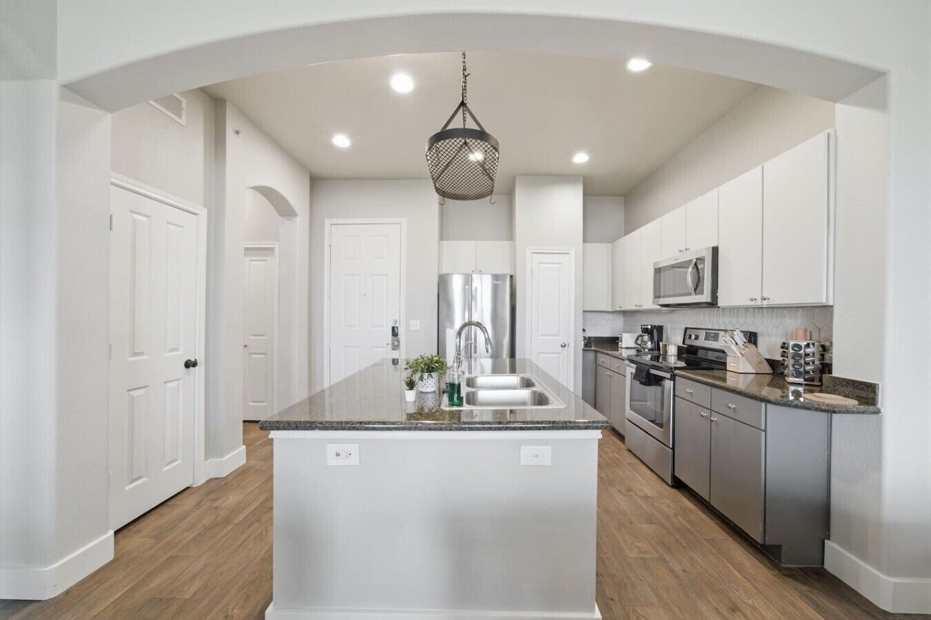 A modern kitchen with white cabinetry, stainless steel appliances, and a central island.