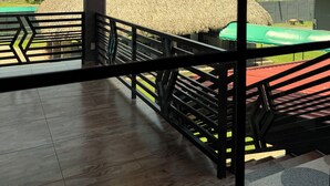 Un espacio interior con techo de madera, una estructura cubierta de paja en el exterior y vistas al verdor.