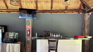 Una zona de bar con mostrador, taburetes, extintor y televisor montado en la pared.