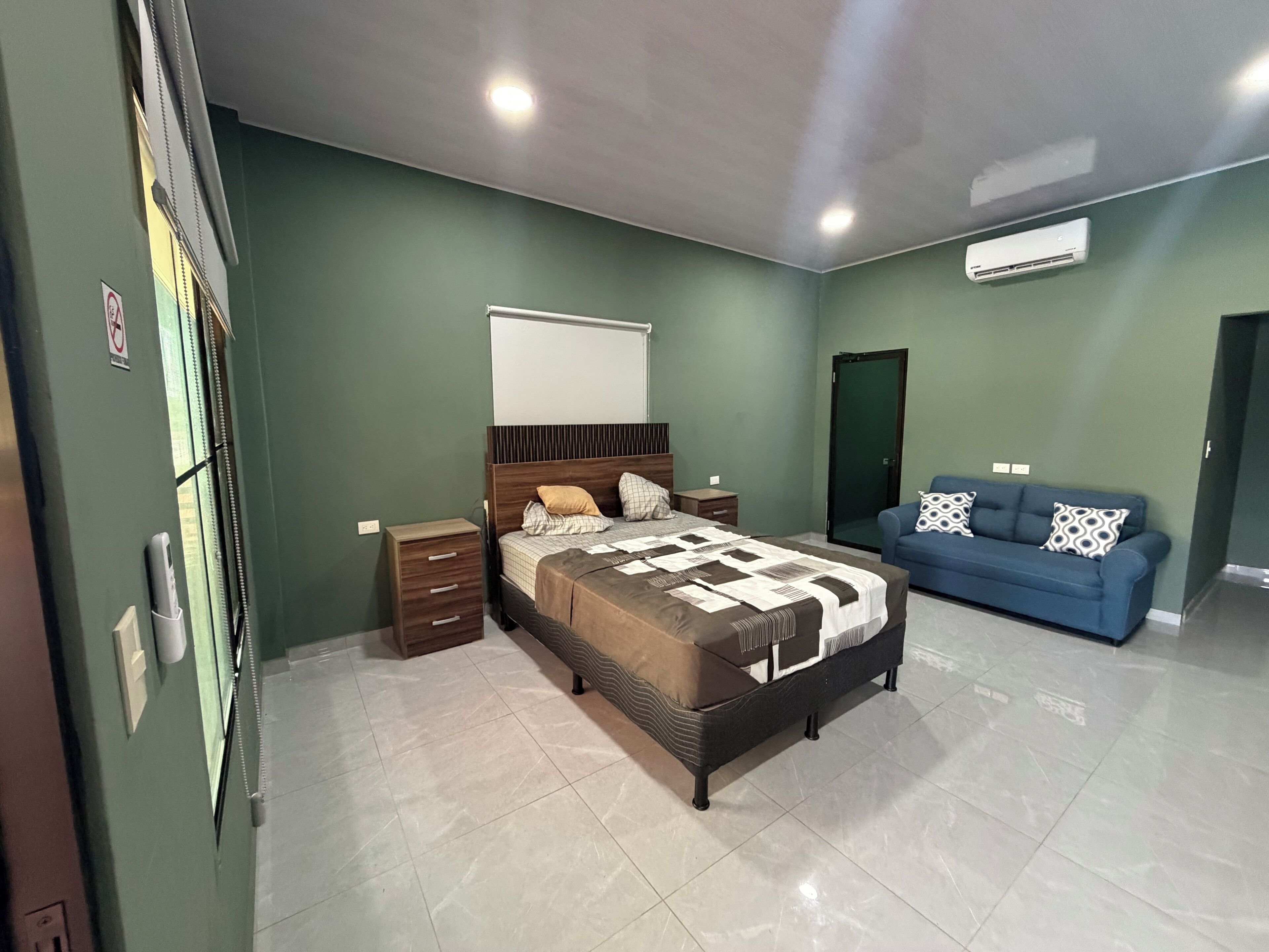 Um quarto com cama, mesas de cabeceira, um sofá azul e um guarda-roupa.