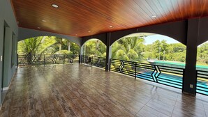 Un espacio interior con techo de madera, varios arcos y vistas al exterior con vegetación.