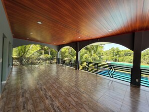An indoor space with a wooden ceiling, multiple arches, and a view of greenery outside.