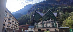 Un edificio con una estructura de tejado verde distintiva, rodeado de un paisaje montañoso.