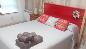 Quarto com cama, janela, radiador e parede com padrão decorativo.