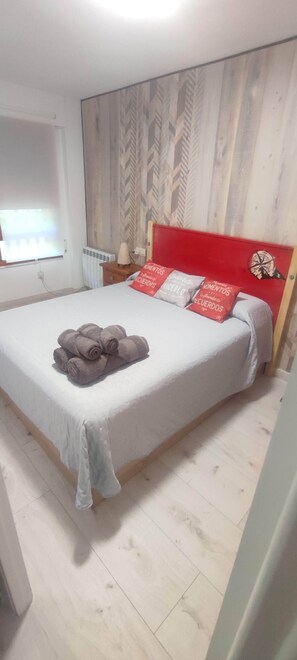 A bedroom with a bed, a window, a radiator, and a wall with a patterned design. - Carlina Canfranc (Canfranc-Estación)