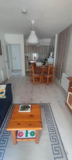 A living room with a dark-colored sofa, a wooden coffee table with a board game, and a patterned rug. - Carlina Canfranc (Canfranc-Estación)
