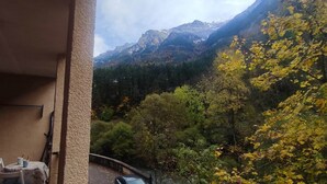Varanda com mesa e cadeiras, vista para uma paisagem montanhosa com folhagem outonal.