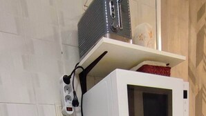 Uma geladeira compacta com compartimento para congelador, um micro-ondas em cima e uma tomada na parede.