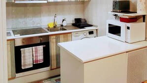 Uma cozinha moderna com armários brancos, uma ilha central e um micro-ondas na bancada.
