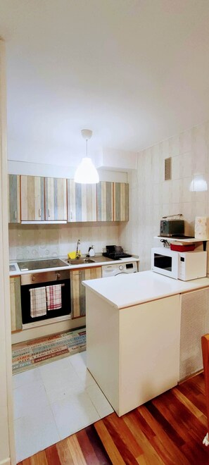 A modern kitchen with white cabinetry, a central island, and a microwave on the countertop. - Carlina Canfranc (Canfranc-Estación)