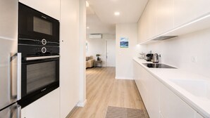 Una cocina moderna con horno Bosch, un lavaplatos de acero inoxidable y encimera blanca.