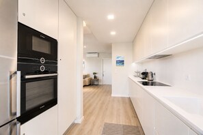 Eine moderne Küche mit einem Bosch-Ofen, einer Edelstahl-Spüle und einer weißen Arbeitsplatte.