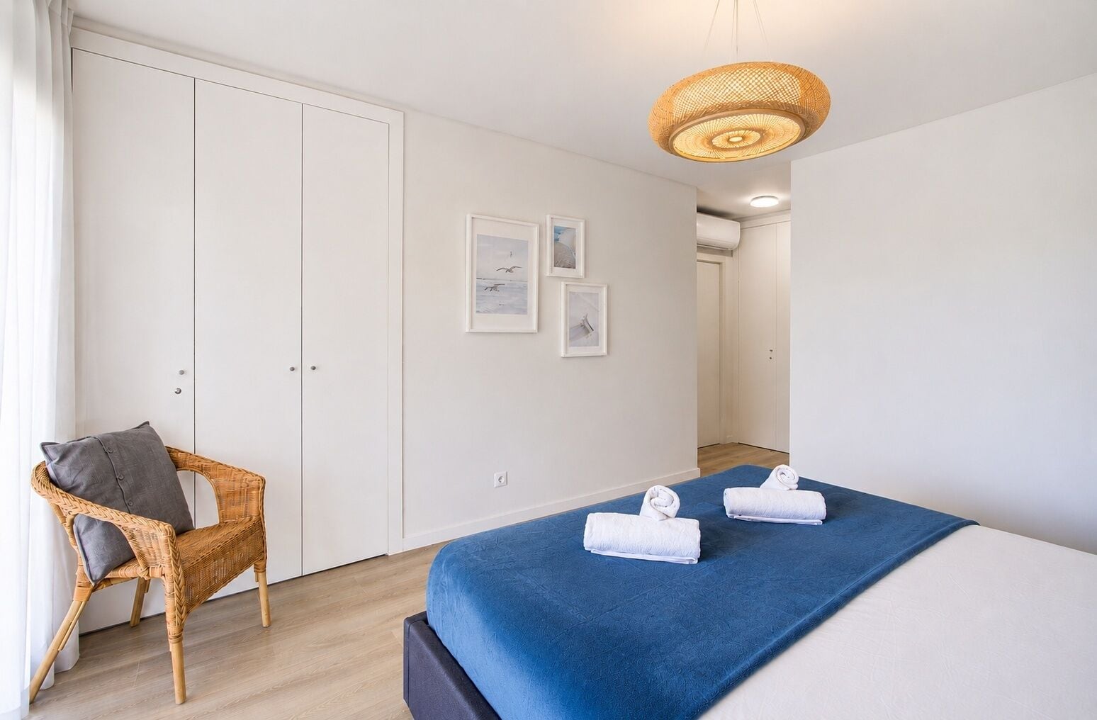 A hotel room with a bed, a chair, and a wardrobe.