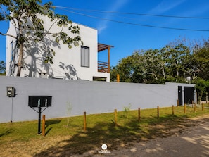 Ein modernes Haus mit weißer Fassade, einem Holzbalkon und einem umzäunten Garten.