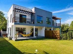 A modern two-story house with a flat roof, large windows, and a covered patio area. - CasAmar a 50m Praia Pontal do Peró - Cabo Frio/RJ (Cabo Frio)