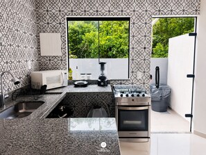 A modern kitchen with a gas stove, a microwave, and a sink. - CasAmar a 50m Praia Pontal do Peró - Cabo Frio/RJ (Cabo Frio)