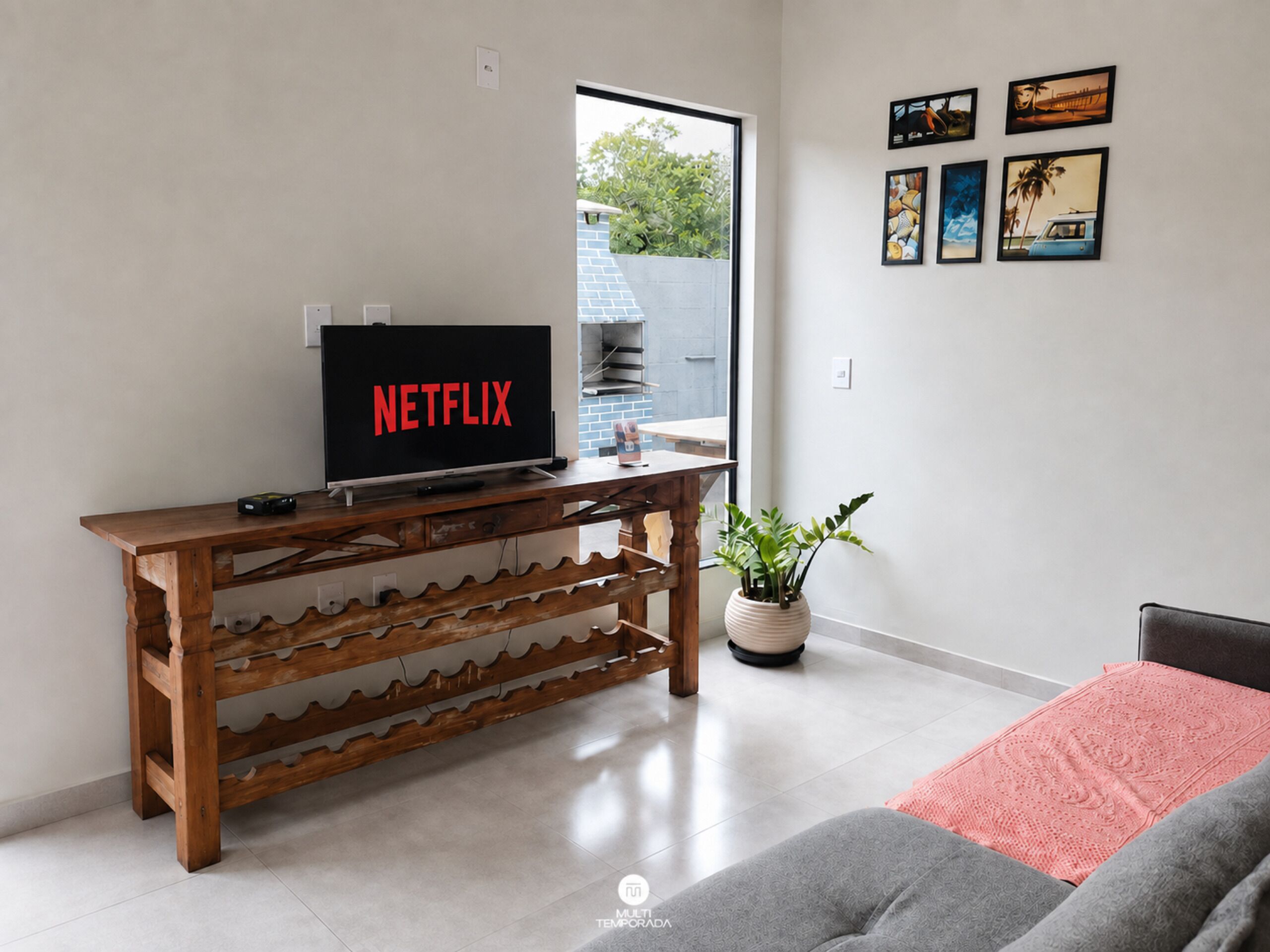 A living room with a wooden TV stand, a potted plant, and a couch.