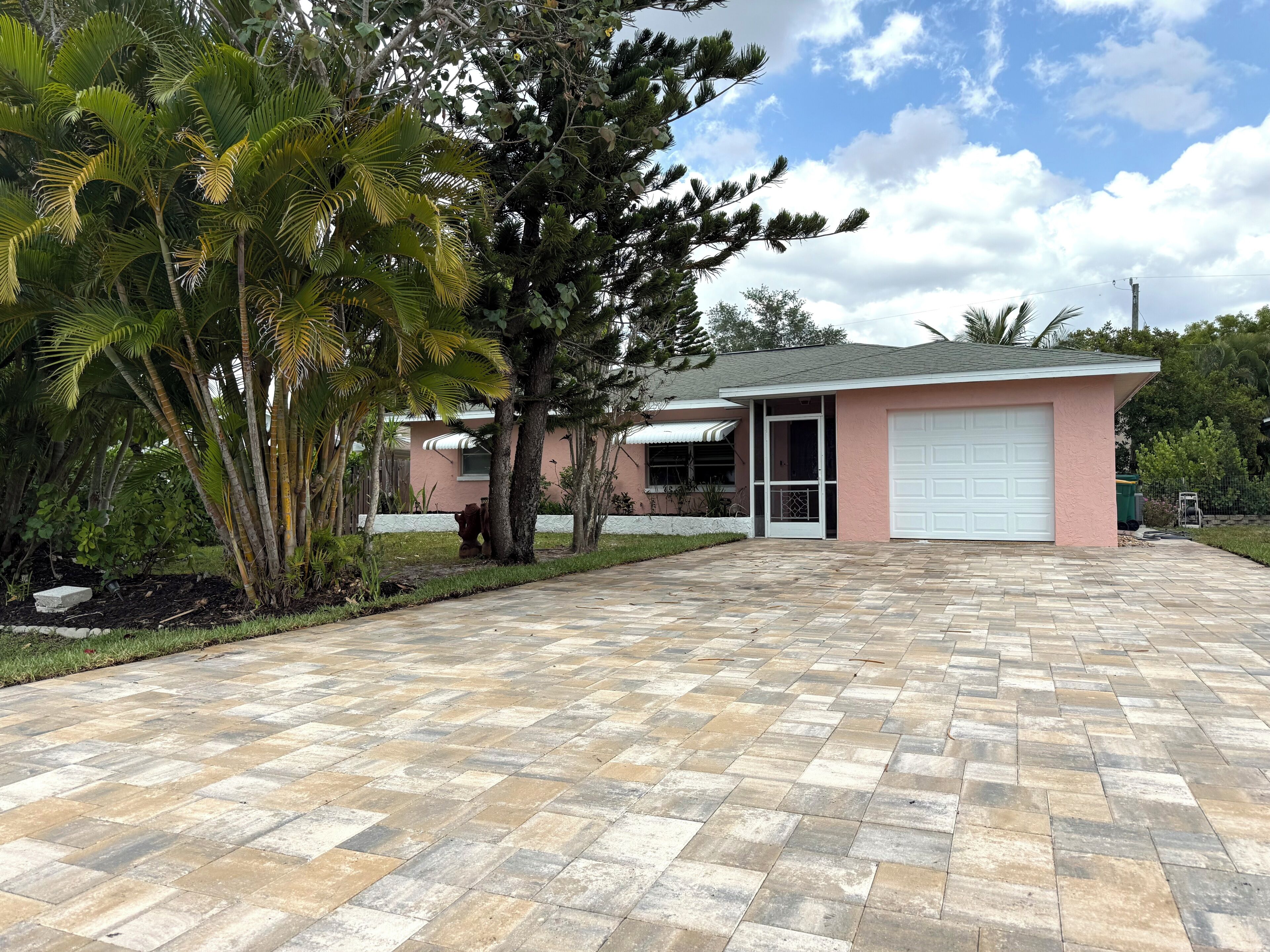 A residential property with a paved driveway, a garage, and a well-maintained lawn.