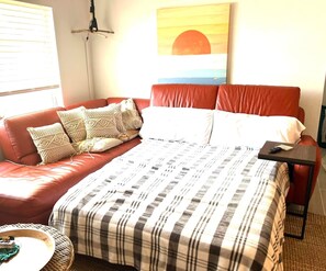 A room with a bed, a red sofa, and a small table. - Bonita Shores Beach House Close to Doc's, Barefoot Beach, Naples +Dog-Friendly! (Bonita Springs)