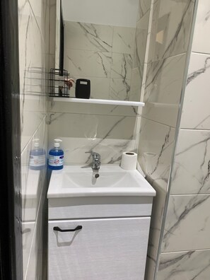 Ein Badezimmer mit einem weißen Waschbecken, einem Spiegel und einer Wand mit Marmorfliesen.