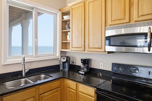 A kitchen with a stainless steel microwave, a coffee maker, and a sink. - Sea Forever SGI Beach Front 5 Bedroom  Hot tub Pool (Saint George Island)