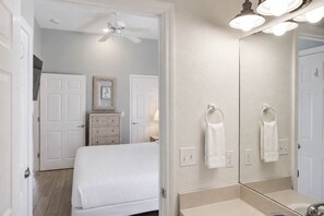 A bedroom with a bed, dresser, and a large mirror above the sink. - Sea Forever SGI Beach Front 5 Bedroom  Hot tub Pool (Saint George Island)