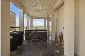 A covered outdoor area with a hot tub, trash bins, and a view of the beach. - Sea Forever SGI Beach Front 5 Bedroom  Hot tub Pool (Saint George Island)