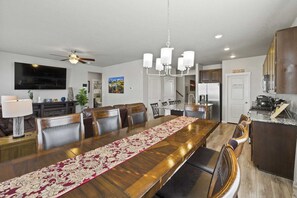 A spacious dining area with a long wooden table, leather chairs, and a chandelier. - Spacious 3-bedroom house with AC in welcoming Colorado Springs (Colorado Springs)