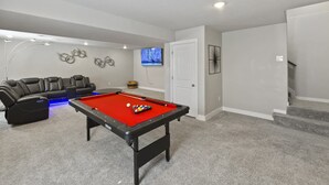A room with a pool table, a sofa, a television, and a door. - Spacious 3-bedroom house with AC in welcoming Colorado Springs (Colorado Springs)
