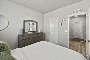 A bedroom with a bed, dresser, mirror, and two doors. - Spacious 3-bedroom house with AC in welcoming Colorado Springs (Colorado Springs)