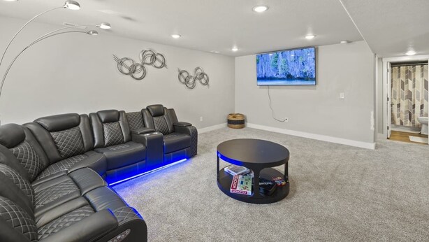 A home entertainment room with a sectional sofa, a round coffee table, and a flat-screen TV mounted on the wall. - Spacious 3-bedroom house with AC in welcoming Colorado Springs (Colorado Springs)