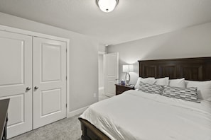 Une chambre d’hôtel avec un grand lit, une table de chevet, une lampe et deux portes.
