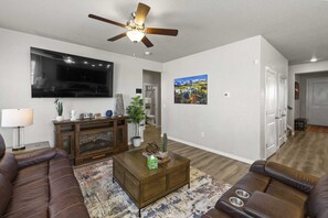 A living room with a fireplace, leather sofas, a coffee table, a TV, and a ceiling fan. - Spacious 3-bedroom house with AC in welcoming Colorado Springs (Colorado Springs)