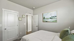 A bedroom with a bed, two doors, a hallway, and a painting on the wall. - Spacious 3-bedroom house with AC in welcoming Colorado Springs (Colorado Springs)