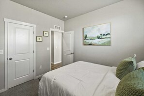 Ein Schlafzimmer mit einem Bett, zwei Türen, einem Flur und einem Bild an der Wand.