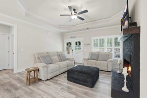 A spacious living room with a ceiling fan, a fireplace, and a view through the windows. - Big Ridge Hideaway - Hot Tub (Talking Rock)