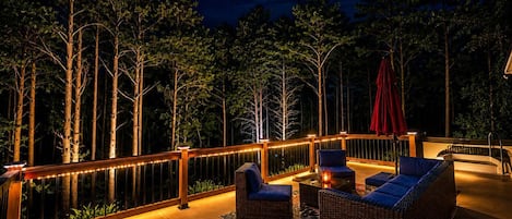 An outdoor deck with a railing, seating area, and a pool.