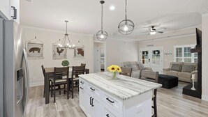 Uma cozinha moderna com ilha de mármore, cadeiras de madeira e luminárias pendentes.