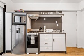 A compact kitchen with a refrigerator, oven, and a small countertop with a coffee maker and cups. - Loft in the Historic Center of the City (Ciudad de México)