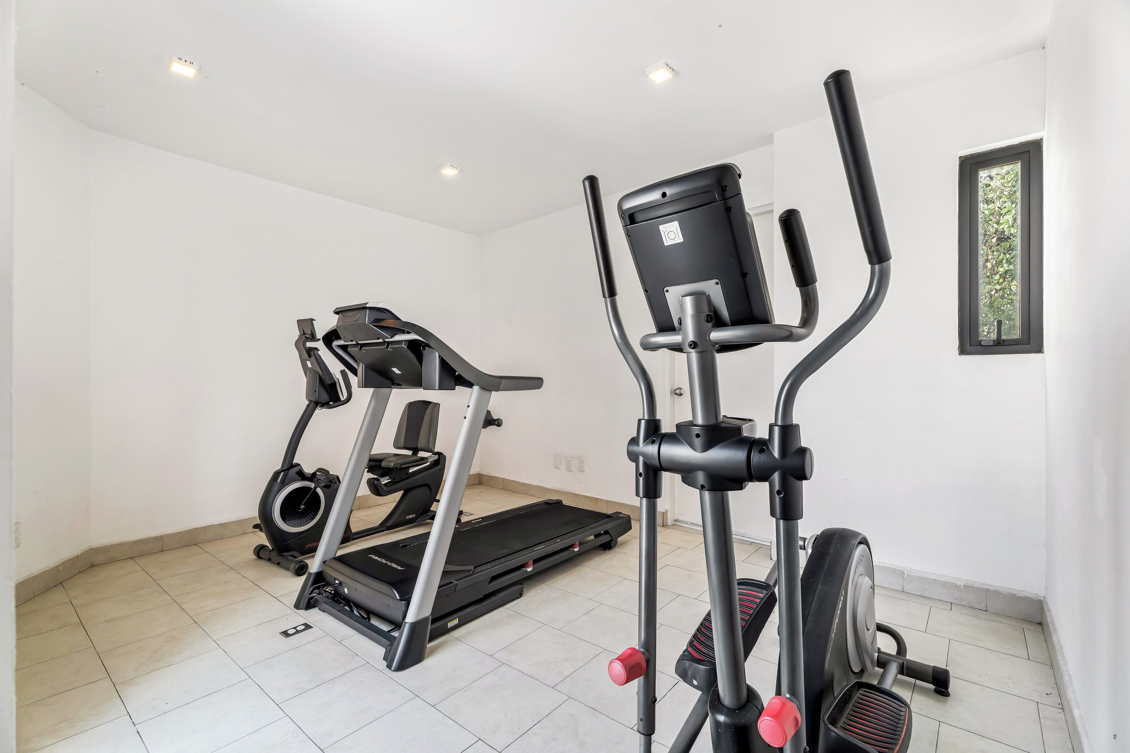 A home gym with a treadmill, elliptical, and stationary bike.