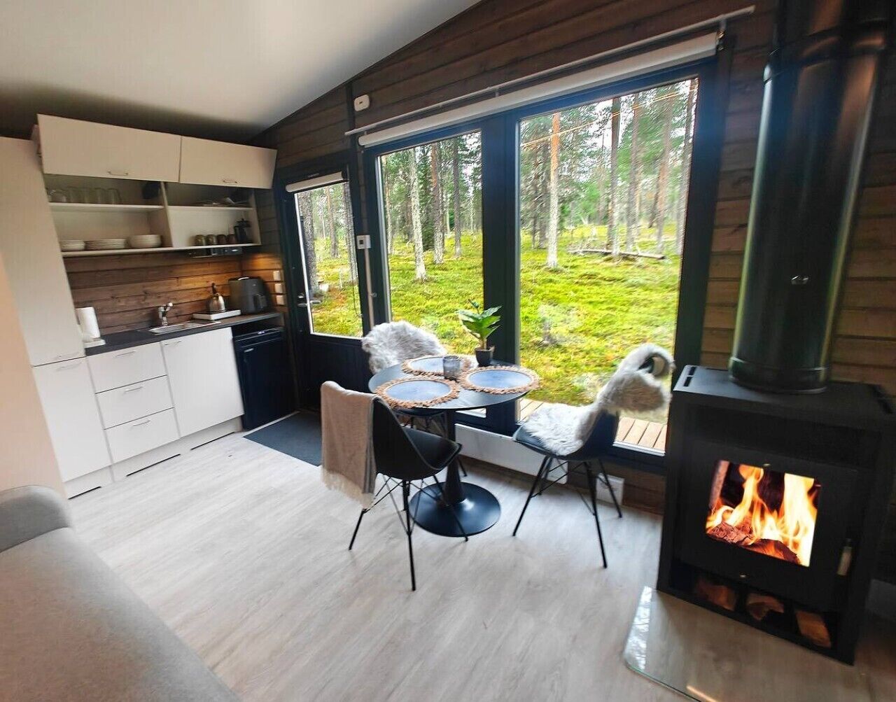 Una cocina moderna con armarios blancos, un comedor con una mesa redonda y sillas, y una estufa de leña.