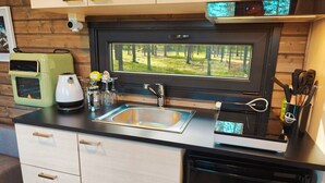 A compact kitchen with a sink, a coffee maker, and a dishwasher.