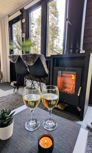 Una habitación acogedora con chimenea, dos copas de vino blanco, una vela y un sillón.